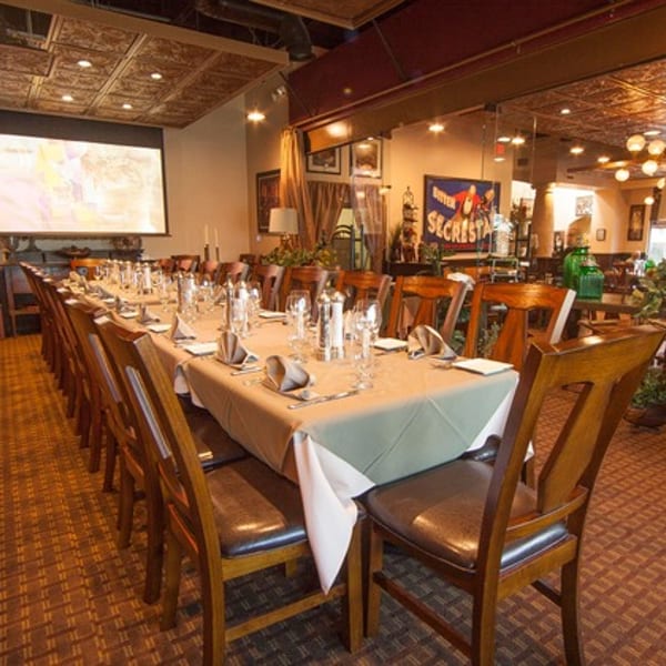 Long dining table set for a private event in a restaurant with a projector screen.