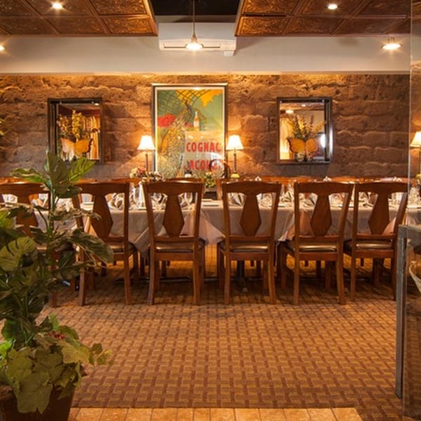Elegant private dining room with a long table set for guests, stone wall, and vintage decor.