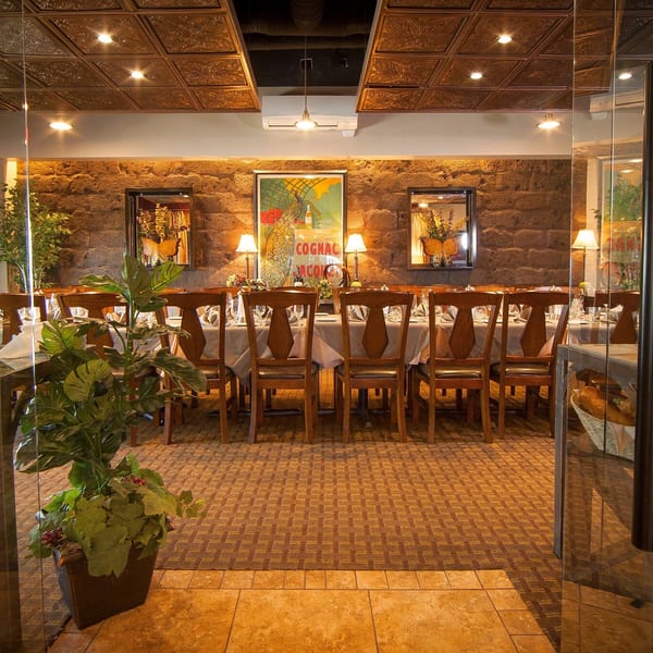 A long dining table set for guests in a private room with stone walls and patterned ceiling.