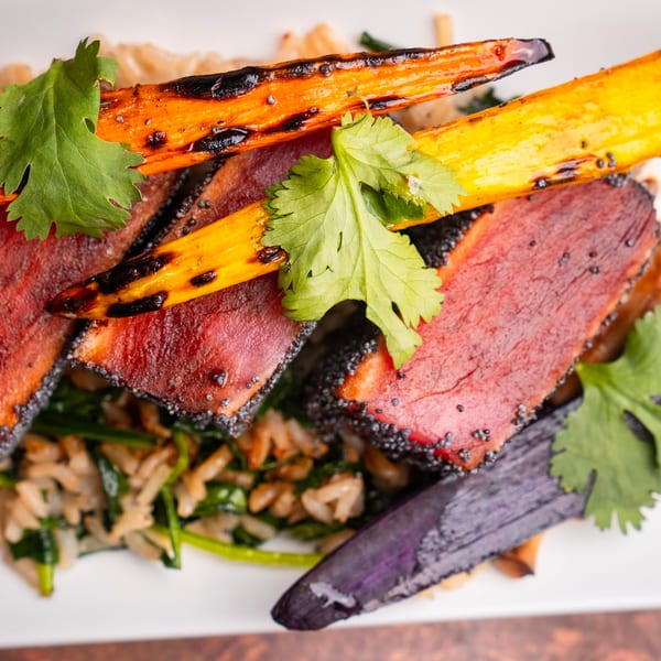Seared tuna with poppy seeds, grilled carrots, and cilantro over rice and spinach.